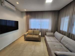 un salon avec un canapé et une télévision dans l'établissement Casa Maré Panaquatira, à São José de Ribamar
