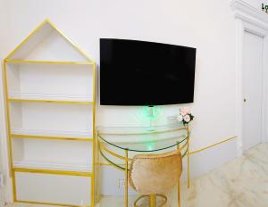 a tv on a wall with a glass table and a chair at Biệt Thự cao cấp Lâu Đài Nhỏ Đà Lạt - Little Castle Da Lat Villa in Da Thien