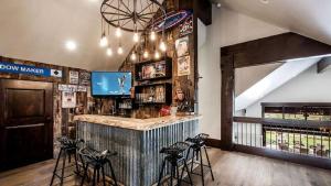 a bar in a restaurant with stools and a tv at Impressive and Secluded Villa for Rent along the Glorious Uinta Mountains, Utah in Oakley +26 photos