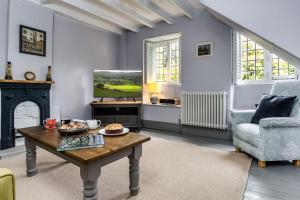 a living room with a table and a tv at 4 Court Cottages in Blockley