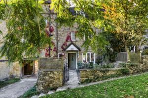 a house with a stone wall and a gate at 4 Court Cottages in Blockley