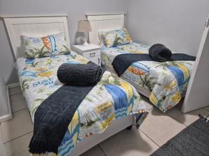 a bedroom with two twin beds with a comforter at Villa Chanel Sea View in Mossel Bay +9 photos