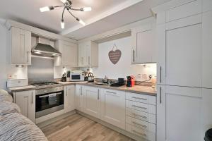 a kitchen with white cabinets and a stove top oven at Finest Retreats - Riverside View in Balloch