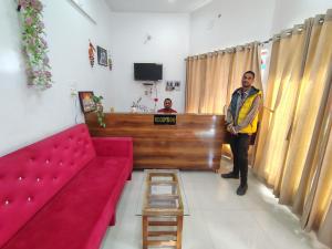 a man standing in a living room with a red couch at Nandin Guest House in Barkot +7 photos