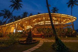 a lit up building with palm trees at night at The Wave , Palolem in Canacona