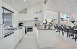 a kitchen with white cabinets and a table and chairs at Cozy Home In Glesborg With Sauna in Fjellerup