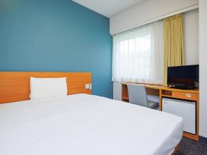 een hotelkamer met een bed, een bureau en een televisie bij Comfort Inn Karuizawa in Karuizawa
