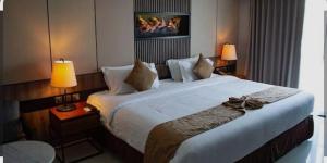 a large bed in a hotel room with two lamps at Friendly Bersama Villa in Medan