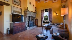 Il comprend un salon doté d'une télévision, d'un canapé et d'une cheminée. dans l'établissement LE MACINE 6, Emma Villas, à Castel del Piano