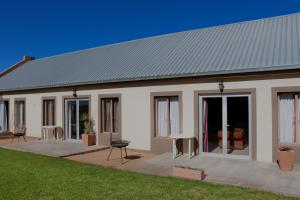 a white house with glass doors and a patio at Grünau Chalets in Khomas Region