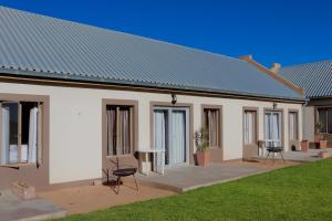Un edificio blanco con una mesa y sillas en un patio. en Grünau Chalets, en Khomas Region