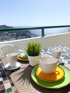 a table with two cups and plates on a balcony at Dreams Paradise Puerto Rico in Puerto Rico de Gran Canaria