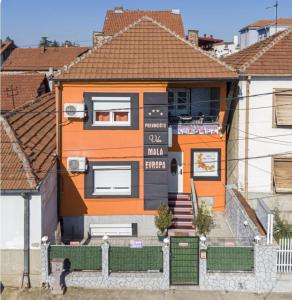 een oranje huis met een bord aan de voorkant bij Vila Mala Evropa in Leskovac