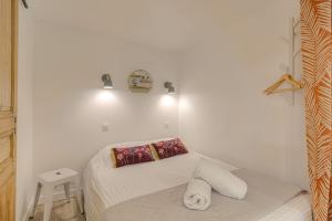a small white bedroom with a bed and a stool at Le Morgon, Studio Confort, proximité Villefranche Centre in Gleizé