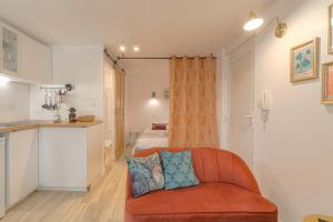 a living room with a orange couch and a kitchen at Le Morgon, Studio Confort, proximité Villefranche Centre in Gleizé +13 photos