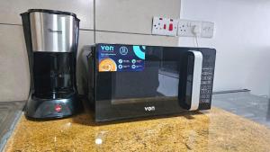 un microondas sentado en un mostrador junto a una licuadora en Hosted by Shee -One bedroom Ruaka near Two Rivers, en Ruaka 3 fotos más