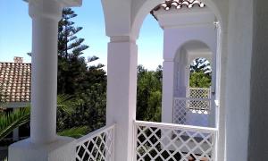 a white porch with an arch and a white fence at APCOSTAS - Complejo Al Andalus in Alcossebre