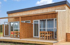 a wooden house with glass doors and tables on a deck at 5 Bedroom Amazing Home In Hanstholm in Pugdal +13 photos