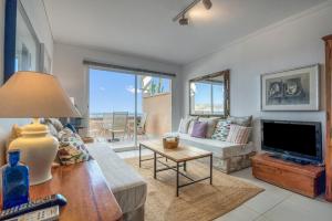 a living room with a couch and a tv at Jávea Beachfront Penthouse in Platja de l'Arenal