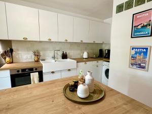 eine Küche mit weißen Schränken und einem Tisch mit Vasen darauf in der Unterkunft Villa Caline, 4 chambres, lotissement calme et proche mer in Lucciana