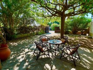 einen Tisch und Stühle unter einem Baum auf einer Terrasse in der Unterkunft Villa Caline, 4 chambres, lotissement calme et proche mer in Lucciana