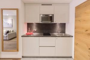 een witte keuken met een spoelbak en een magnetron bij Apartment Crown Andermatt-16 in Andermatt