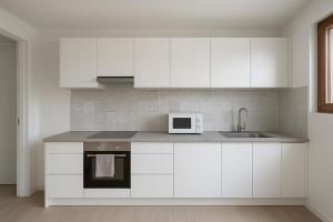 een witte keuken met een spoelbak en een magnetron bij La Grande Maison Paris Sud in Vitry-sur-Seine