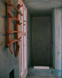 een badkamer met douche en een deur met boomstammen aan de muur bij Folegandros Villas Beachfront in Karavostasi
