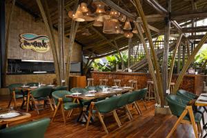 a restaurant with wooden tables and green chairs at The Wave , Palolem in Canacona