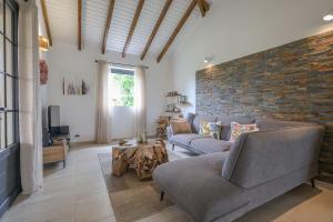 a living room with a couch and a brick wall at L Échappée Belle Havre de paix au cœur du verger in Le Moule
