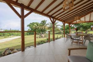 a large covered porch with a table and chairs at L Échappée Belle Havre de paix au cœur du verger in Le Moule