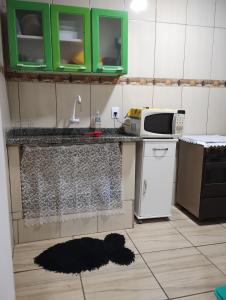 a kitchen with green cabinets and a black rug on the floor at Sobrado Frescor do Mar! in Cabo Frio