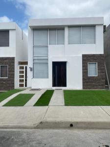 a white house with a front door and grass at Welcome to your perfect Manta Coast getaway in Manta