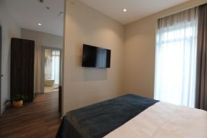 una camera da letto con un letto e una televisione a parete di White Hill Hotel a Tbilisi City Altre 57 foto