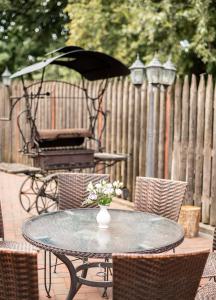 a glass table with a vase of flowers on a patio at Arti Minijos - mažoji salė in Priekulė