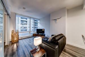 ein Wohnzimmer mit Ledercouch und Fernseher in der Unterkunft Corporate Stays Tate 1 Bedroom in Vancouver