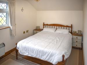 a bedroom with a bed with white sheets and a window at Orchardlea Apartment in Coldridge