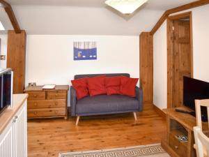 a living room with a blue couch with red pillows at Orchardlea Apartment in Coldridge