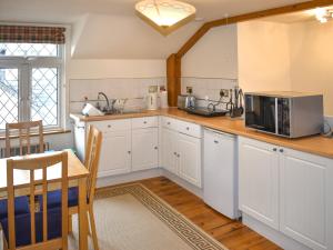 a kitchen with white cabinets and a microwave at Orchardlea Apartment in Coldridge