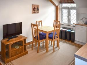 a dining room with a table and a television at Orchardlea Apartment in Coldridge