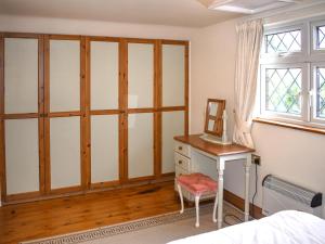 a bedroom with a dresser and a desk and a window at Orchardlea Apartment in Coldridge +3 photos