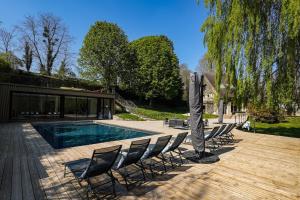 eine Gruppe von Stühlen und ein Pool mit einem Sonnenschirm in der Unterkunft La Villa du Cinéma 