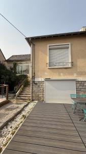 Ein Haus mit zwei Garagentoren und einer Holzterrasse in der Unterkunft L Atypique Briviste - Villa Montyon in Brive-la-Gaillarde