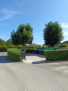 a parking lot with two trees and bushes at Leo Lagrange in Champforgeuil