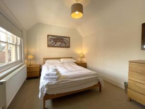 a bedroom with a bed with white sheets and a window at Sterling House in Robin Hood's Bay