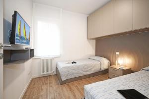 Un dormitorio con dos camas y un televisor de pantalla plana. en Appartamenti La Torre, en Lazise