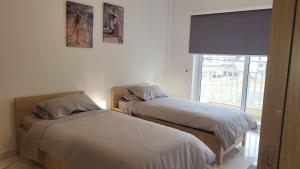 two beds in a room with a window at Flat 1 Central Apartment in Swieqi in Is-Swieqi