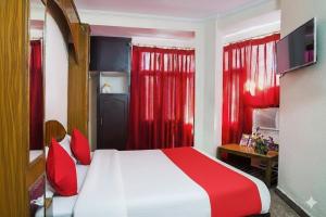 a bedroom with a red and white bed and red curtains at Raghunath Jammu in Jammu