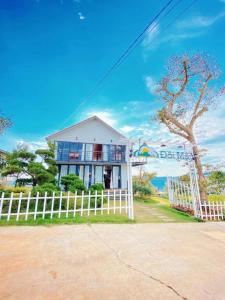 a white house with a fence in front of it at Homestay Đồi Mây Lộc Tân Bảo Lộc in Bảo Lâm