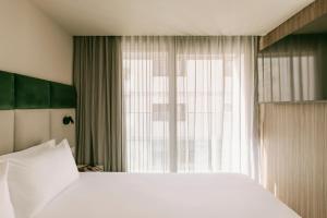 a bedroom with a large white bed and a window at Regional Hotel by NEU Collective in Il-Gżira